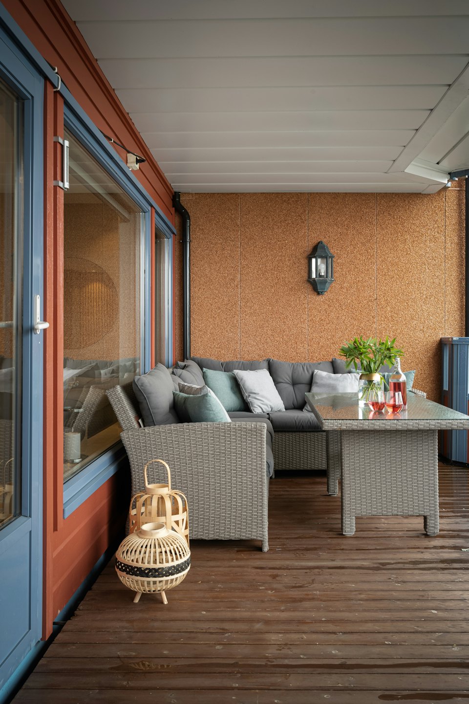 Rattan sectional sofa and table on a wooden deck.