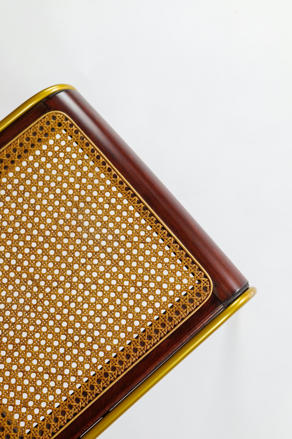 Intricate woven cane chair seat with dark wood and gold trim.