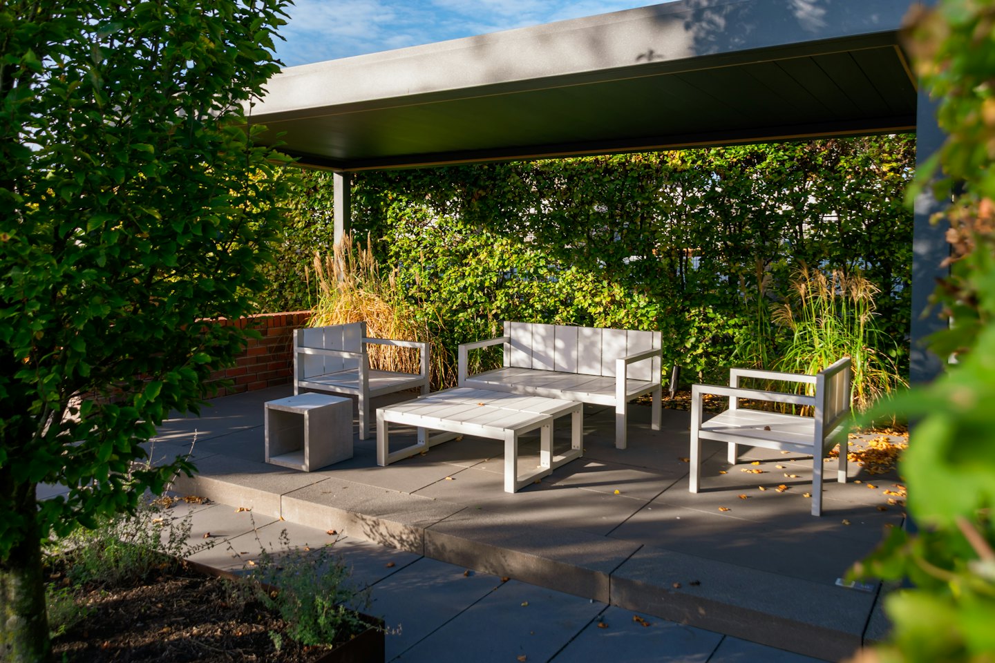 White patio furniture arranged on a paved outdoor terrace.