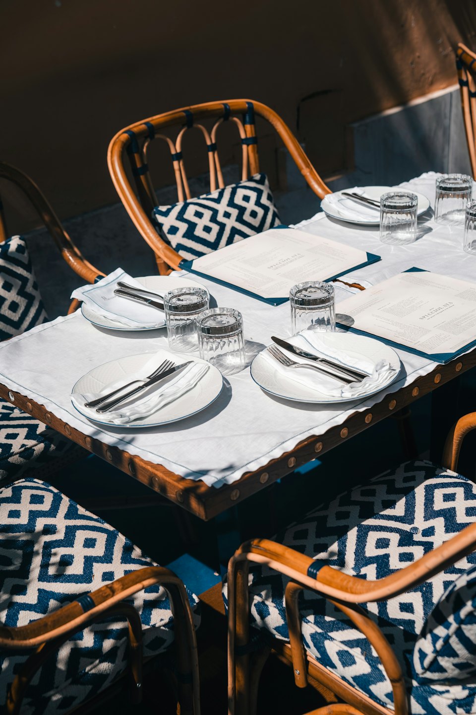 Outdoor dining table set with blue cushions and white tablecloth.